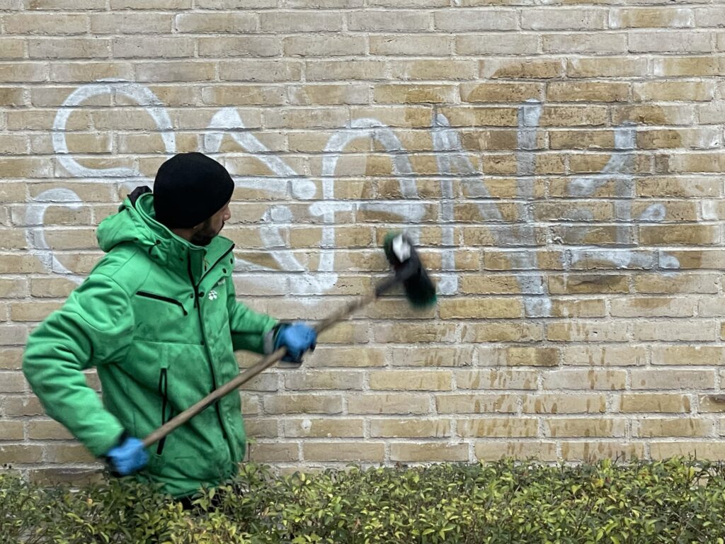 Skånsom fjernelse af graffiti, hvor det korrekte middel bliver skrubbet på graffitien